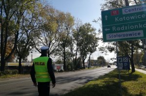 policjant przy trasie i tablicy informacyjnej