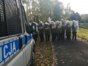 policjanci przemieszczają się obok radiowozu