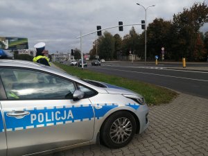 policjant ruchu drogowego stojący przy radiowozie przy ulicy