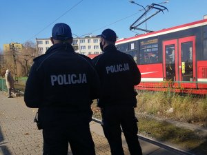 Policjanci na przystanku w tle jedzie tramwaj