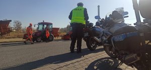 Policjant przy motocyklach policyjnych w tle traktor