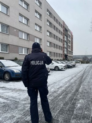 policjantka rozmawia przez telefon przed blokiem