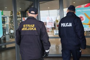 policjant i strażnik miejski wchodzą do centrum handlowego