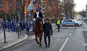 Na prowadzonym koniu jedzie król z Orszaku Trzech Króli w tle radiowóz