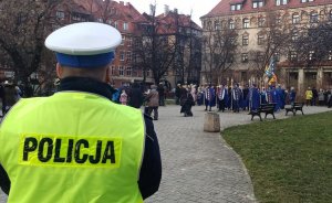 Policjant, w tle grupa osób z Orszaku Trzech Króli