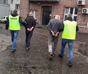 Policjanci doprowadzają dwóch zatrzymanych mężczyzn