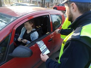 Drogówka wręcza kobiecie w pojeździe ulotkę