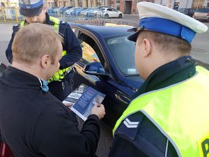 Policjant daje ulotkę mężczyźnie