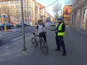 Policjant wręcza ulotkę rowerzyście