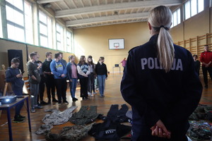 Policjantka stoi przodem do uczniów w sali gimnastycznej