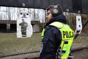 Policjant stoi przed tarczami na strzelnicy