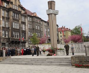 Pomnik i w oddali przedstawiciele władz miasta, służb mundurowych