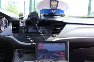 W radiowozie ekran z nagraniem jadących pojazdów i czapka policyjna