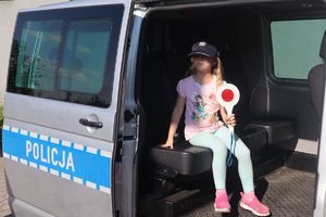 Dziewczynka z tarczą do zatrzymywania pojazdów siedzi w radiowozie