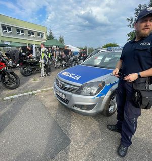 Policjant przy radiowozie, a w tle motocykle.