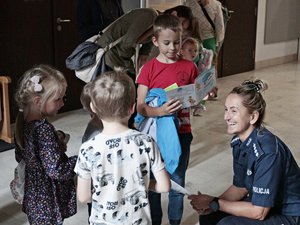 Policjantka rozdaje książeczki dzieciom