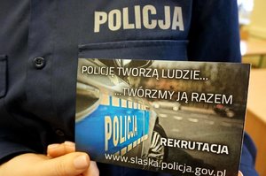 Policjantka trzyma plakat z napisem &quot;Policję tworzą ludzie...twórzmy ją razem&quot;.