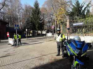 Policjant stoi przy motocyklu policyjnym, w tle widoczna ulica , znak zakaz wjazdu i policjanci.