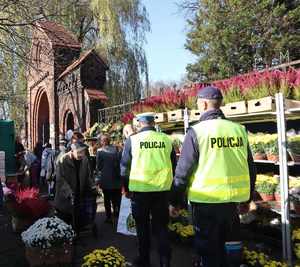 Policjanci przy bramie cmentarnej.