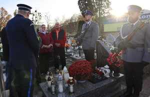 Zastępca Komendanta Miejskiego Policji w Bytomiu na cmentarzu oddaje hołd poległemu policjantowi, przy grobie warta honorowa.