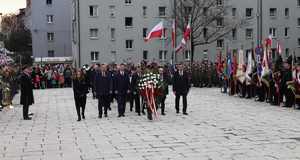 Delegacja z kwiatami na placu przed pomnikiem.