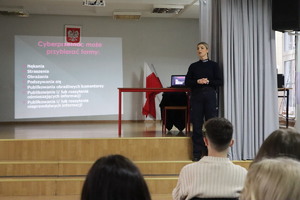 Na zdjęciu widoczna w auli szkoły policjantka i uczniowie.