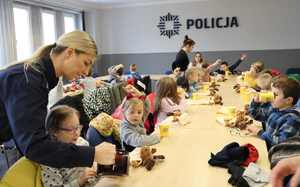 Na zdjęciu widoczna aula Komendy Miejskiej Policji w Bytomiu i policjantka, która nalewa dzieciom herbatę.