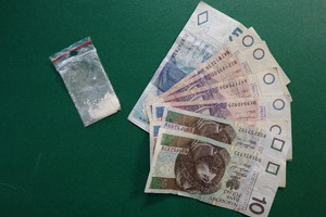 Zdjęcie przedstawia narkotyki w woreczku foliowym i różne banknoty polskich pieniędzy