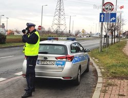 Policjant ruchu drogowego mierzy prędkość, zanim widoczny radiowóz.