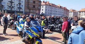 Chłopiec siedzący na policyjnym motocyklu w obecności policjanta