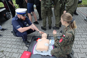 Policjant wyjaśniający uczennicy zasady udzielania pierwszej pomocy