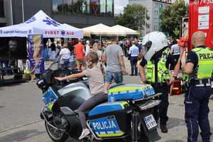 Dziewczynka siedząca na motorze, policjanci, uczestnicy pikniku.