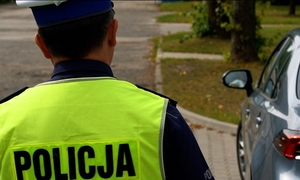 Zdjęcie przedstawia policjanta, który podchodzi do samochodu.