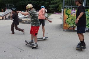 Zdjęcie przedstawia dzieci i młodzież korzystające ze skateparku.