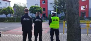 policjant i uczniowie klasy policyjnej stojący przy drodze