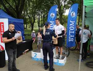 Na zdjęciu widzimy policjantkę, która wręcza medal zwycięzcy jednej z kategorii wyścigów rowerowych.