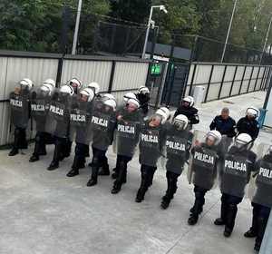 Zdjęcie przedstawia policjantów na stadionie w sprzęcie ochrony indywidualnej.