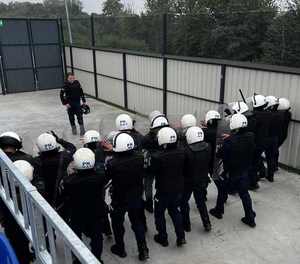 Na zdjęciu widzimy na stadionie szkolących się policjantów w sprzęcie ochrony indywidualnej i instruktora.