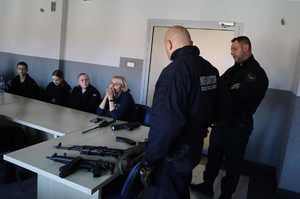 Na zdjęciu widzimy policjantów w tym instruktora wyszkolenia strzeleckiego, który pokazuje jednostki broni uczniom klasy mundurowej.