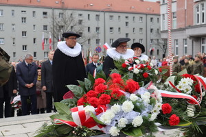 Na zdjęciu widzimy uczestników uroczystości składających kwiaty pod pomnikiem.