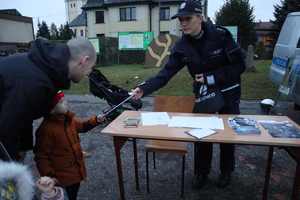 Na zdjęciu widzimy, jak policjantka podaje chłopcu odblask.