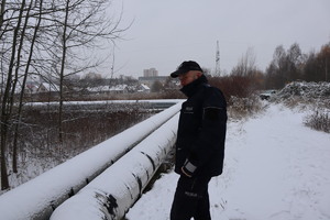 Na zdjęciu policjant rozgląda się, widoczne rury ciepłownicze.