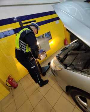 Na zdjęciu policjant sprawdza oświetlenie pojazdu.