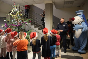 Na zdjęciu widzimy Komendanta Miejskiego Policji w Bytomiu, śląską maskotkę Policji Sznupka, dzieci i choinkę.