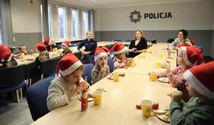 Na zdjęciu widzimy dzieci i policjantkę przy słodkim poczęstunku.