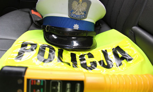 Na zdjęciu widzimy czapkę policyjną, kamizelkę odblaskową z napisem Policja i alkomat.