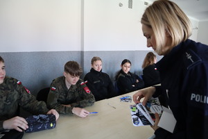 policjantka rozdająca uczniom ulotki i długopisy