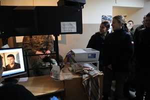 uczniowie klasy mundurowej przyglądający się technikowi kryminalistyki wykonującemu zdjęcia sygnalityczne