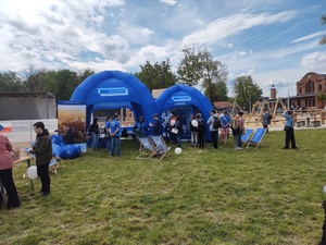 Na zdjęciu dwa niebieskie namioty, na nich napis: fundusze europejskie. Przed nimi krzesła i zgromadzone osoby.