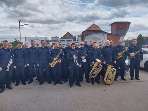 Na zdjęciu kilkudziesięciu policjantów w mundurach, część trzyma w ręku instrumenty.